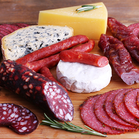 Assortment of smoked sausages and cheese on cutting board and wo Articolo15 HeaderMobile 1