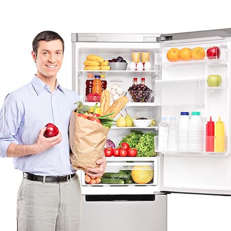 Smiling man holding a bag in front of refrigerator full of produ Articolo25 HeaderMobile 1